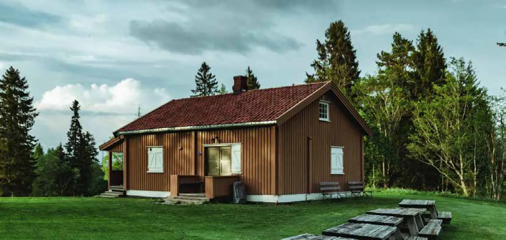 Maison en bois dans un environnement rural entouré d’arbres et d’herbe