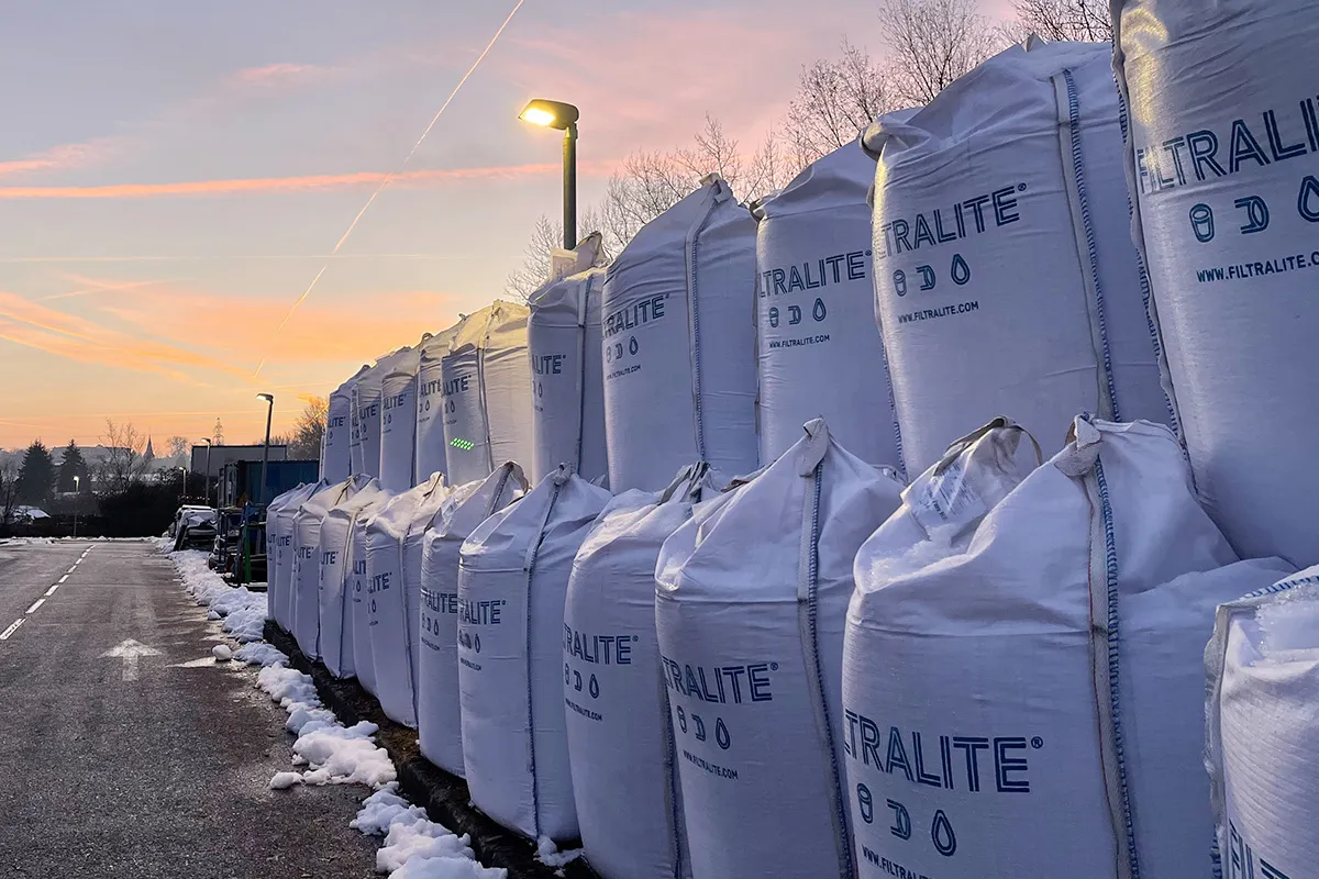 Piles de grands sacs blancs Filtralite alignés à l’extérieur au coucher du soleil, avec de la neige au sol