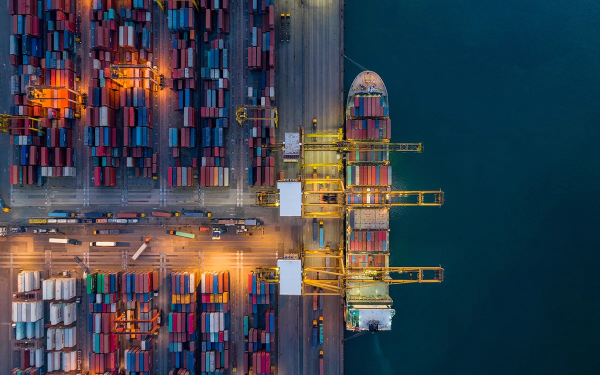 Vue aérienne d’un port animé avec des conteneurs et un navire à quai de nuit