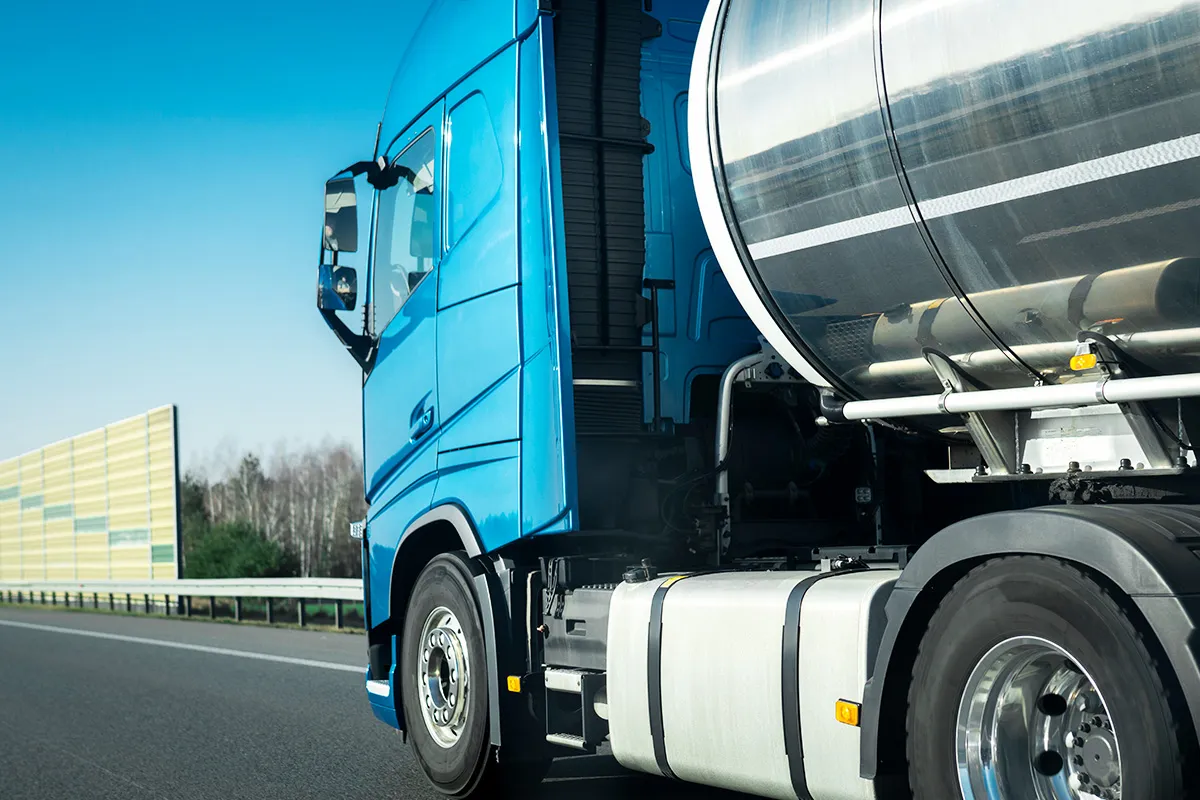 Gros plan d’un camion bleu roulant sur une autoroute avec une citerne en acier inoxydable