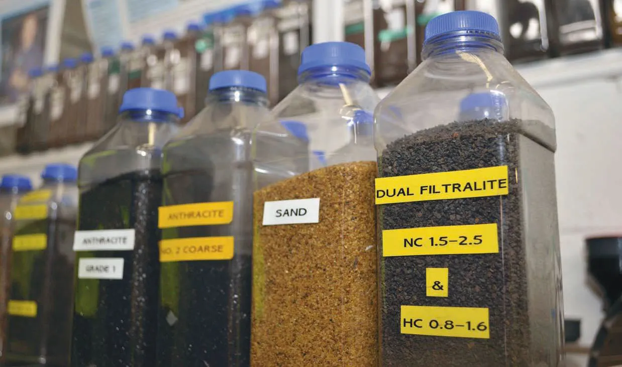 Close-up of various water filter media samples, including sand, anthracite, and Filtralite Pure Mono-Multi, labeled and displayed in transparent containers
