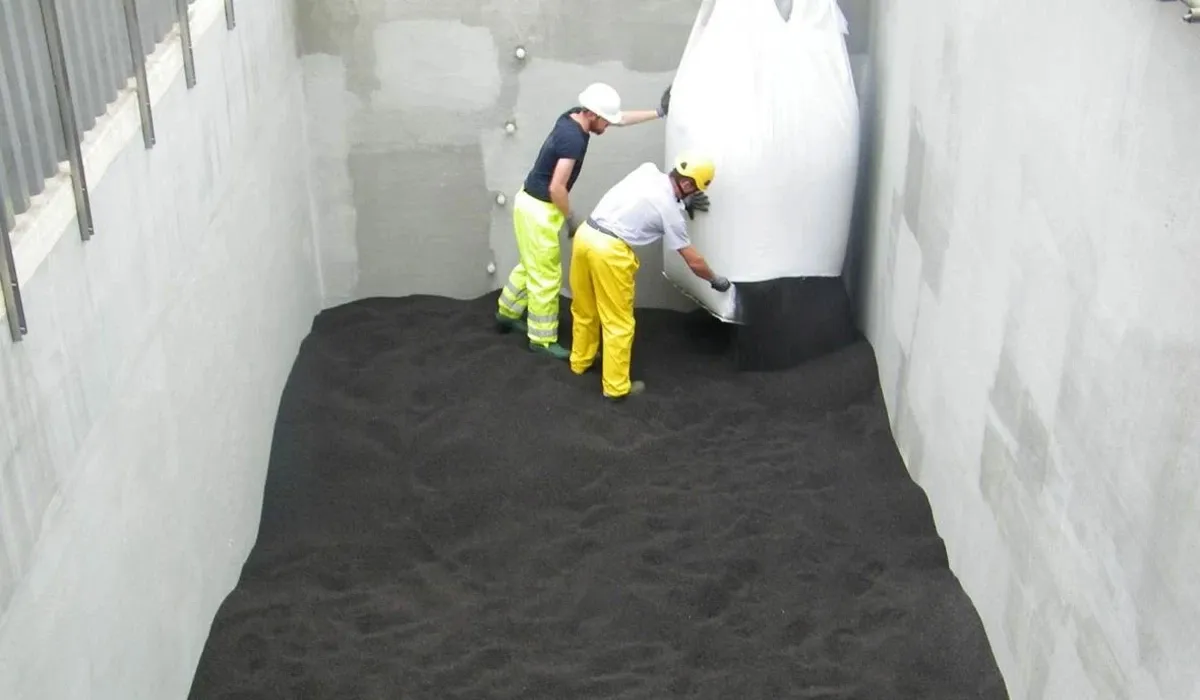 Deux opérateurs déversant le média filtrant Filtralite à partir d’un big bag blanc dans une cuve detraitement d’eau