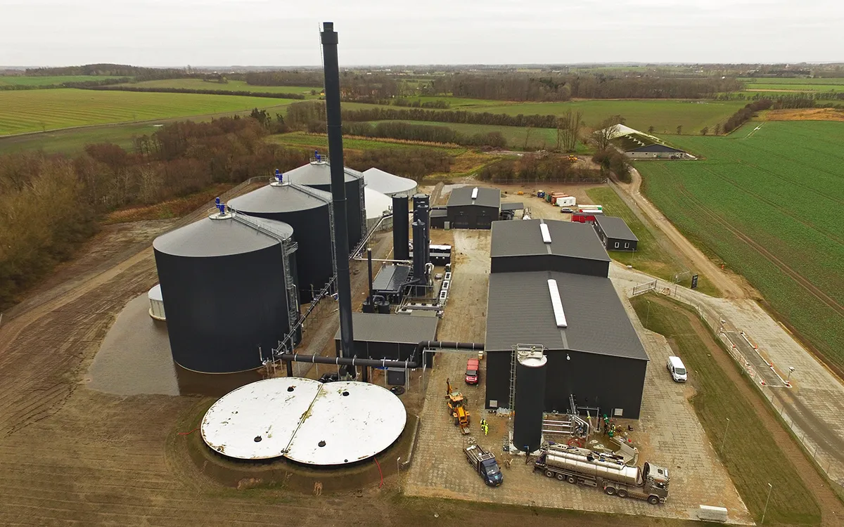 Aerial view of the Nature Energy Nordfyn biogas plant with three large biogas reactors on the left and the odour filter with a white lid in the foreground