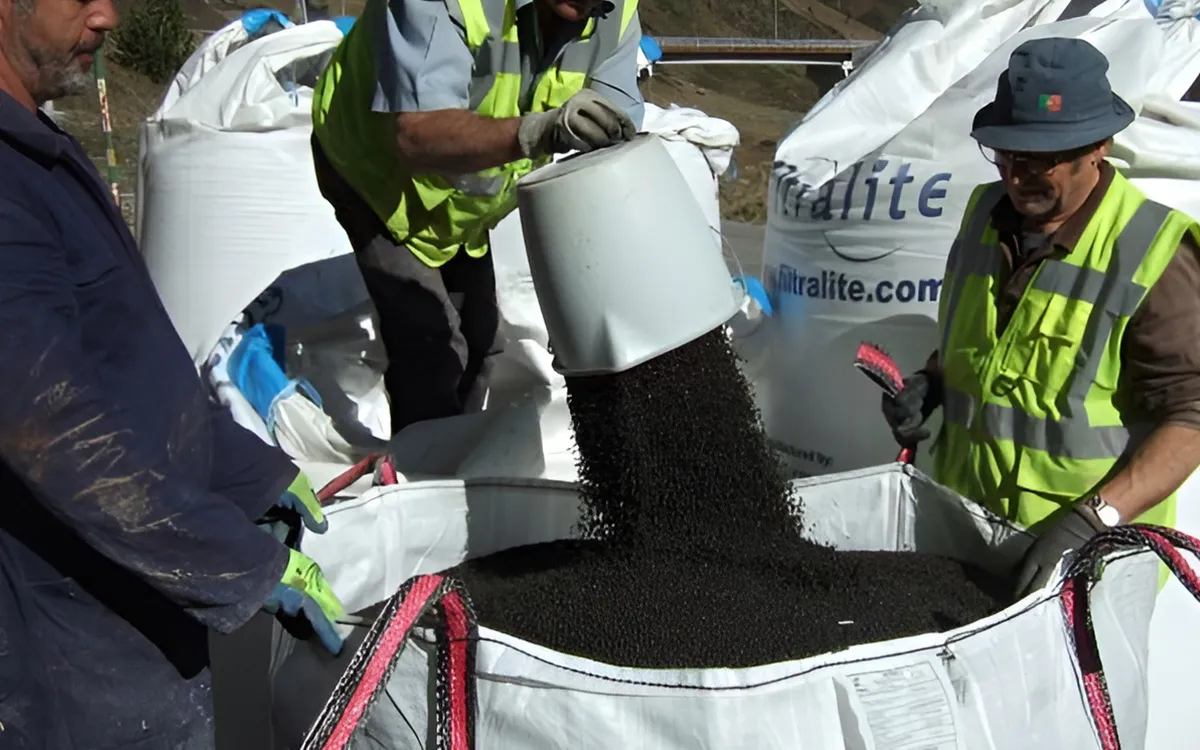 Opérateurs remplissant de grands big-bags de média filtrant Filtralite sur le site de la stationd’épuration du Pas de la Case
