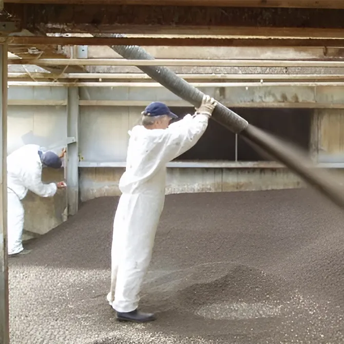 Workers in protective clothing installing Filtralite Air filter media using a blower hose inside a purification system at Novozymes’ facility